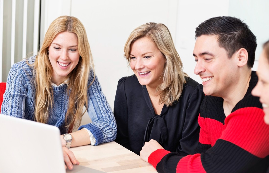 Two women and a man sitting infront of a laptop.