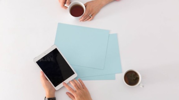 A discussion table with blue papers, coffee and a digital pad